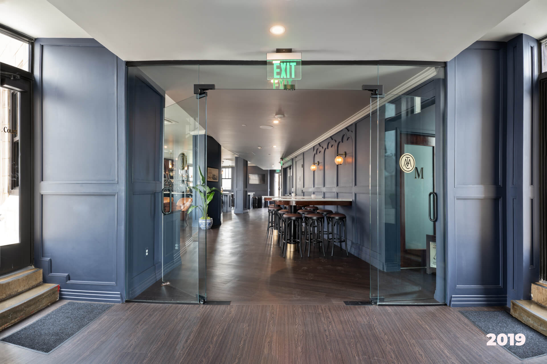 After construction, The Monarch Club has glass doors, navy walls, and new wood floors.